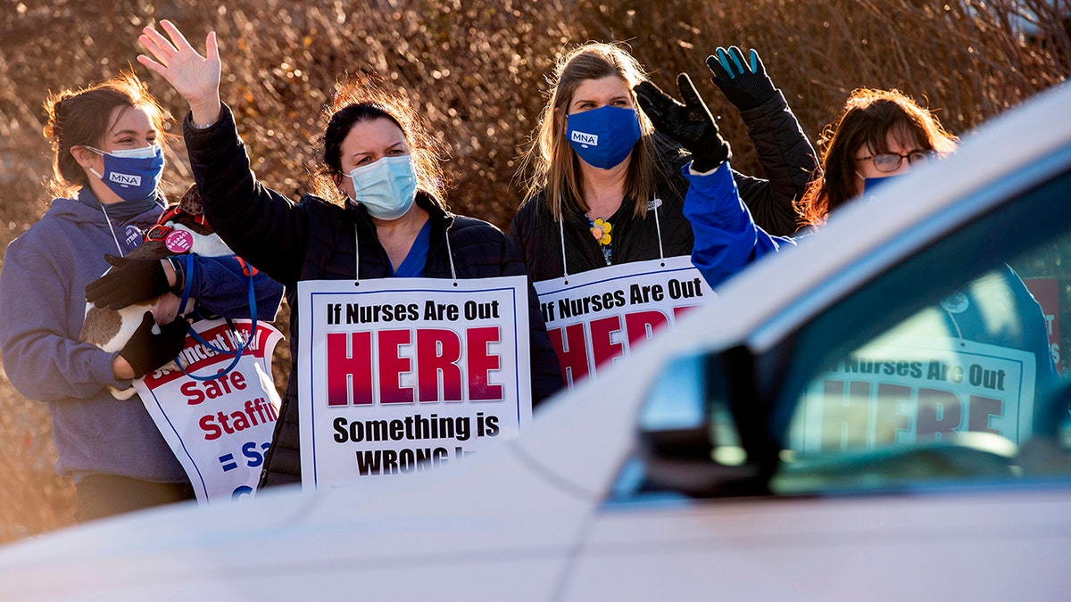 Registered nurses and supporters stand in a picket line and wave to cars as they drive by outside St. Vincent Hospital in Worcester, Massachusetts, on February 24, 2021. 