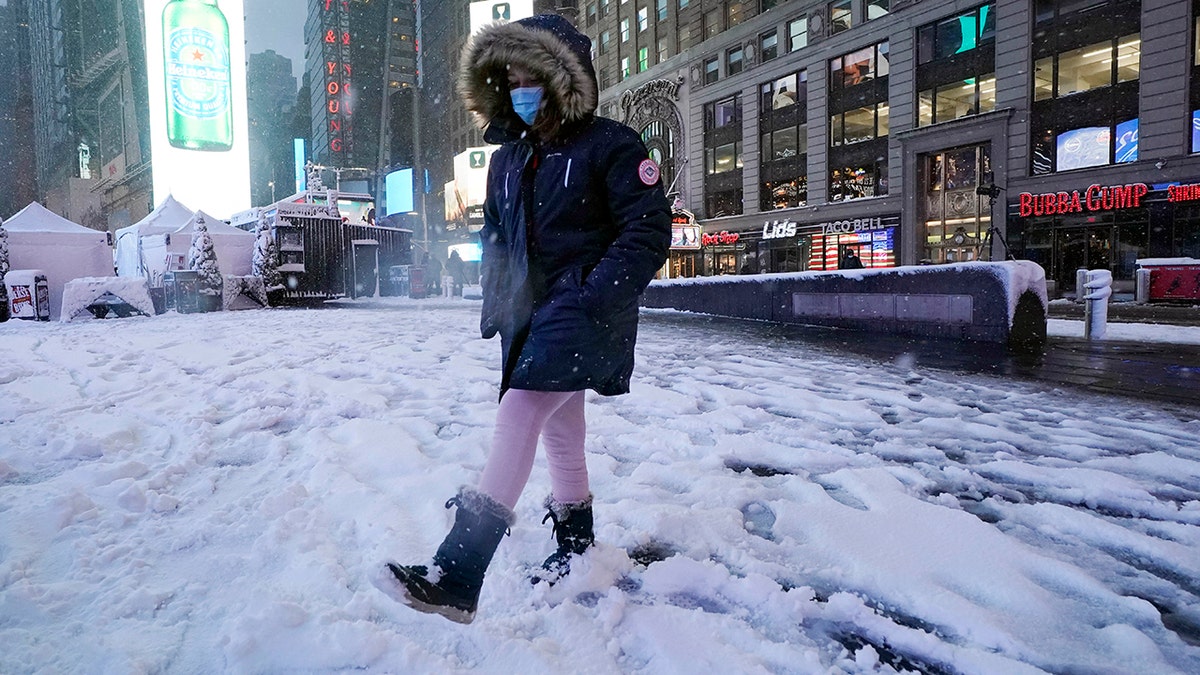 A girls kicks at snow in New York's Times Square, Friday, Jan. 7, 2022.