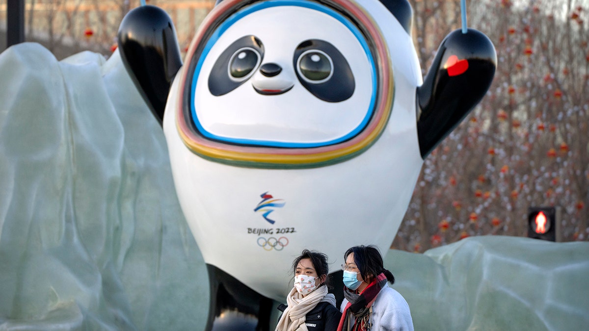 People wearing face masks to protect against coronavirus walk past a statue of the Winter Olympic mascot Bing Dwen Dwen near the Olympic Green in Beijing, Wednesday, Jan. 12, 2022.