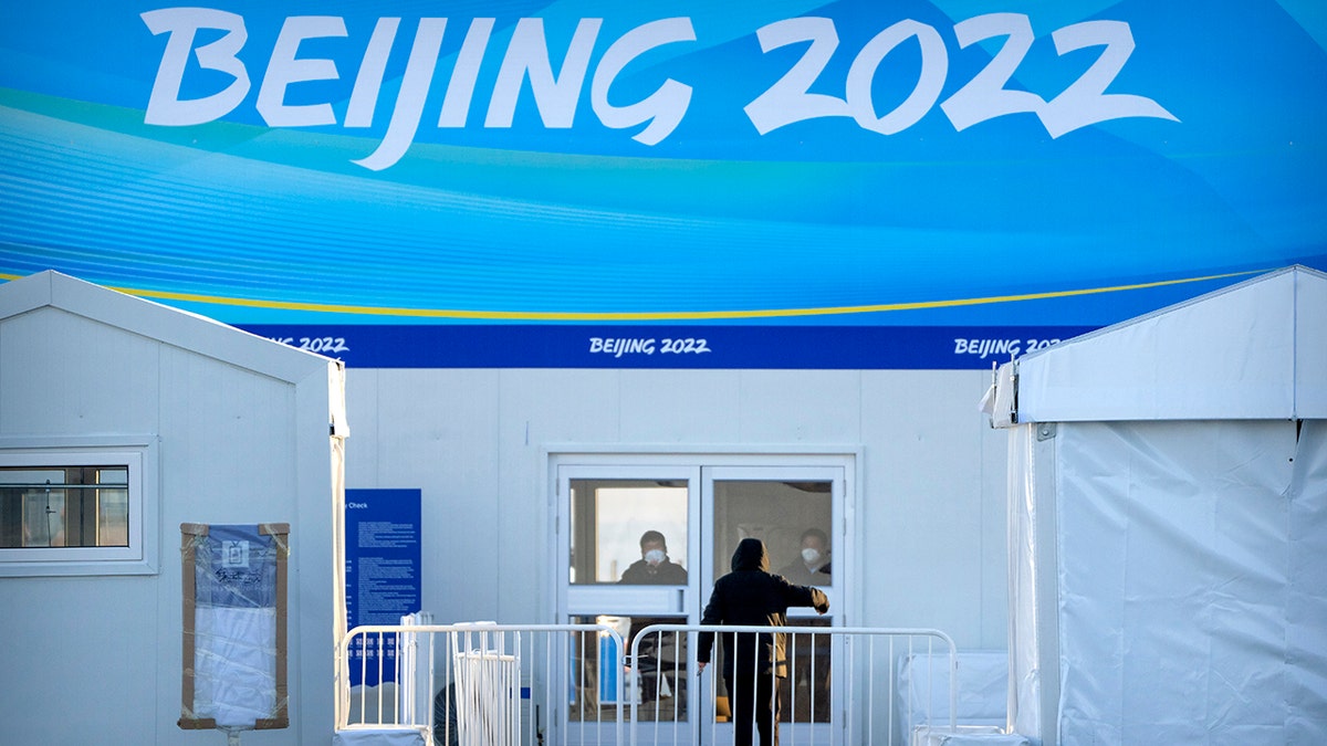 Workers wearing face masks to protect against coronavirus stand inside a screening area for Winter Olympic spectators set up near the Olympic Green in Beijing, Wednesday, Jan. 12, 2022. 