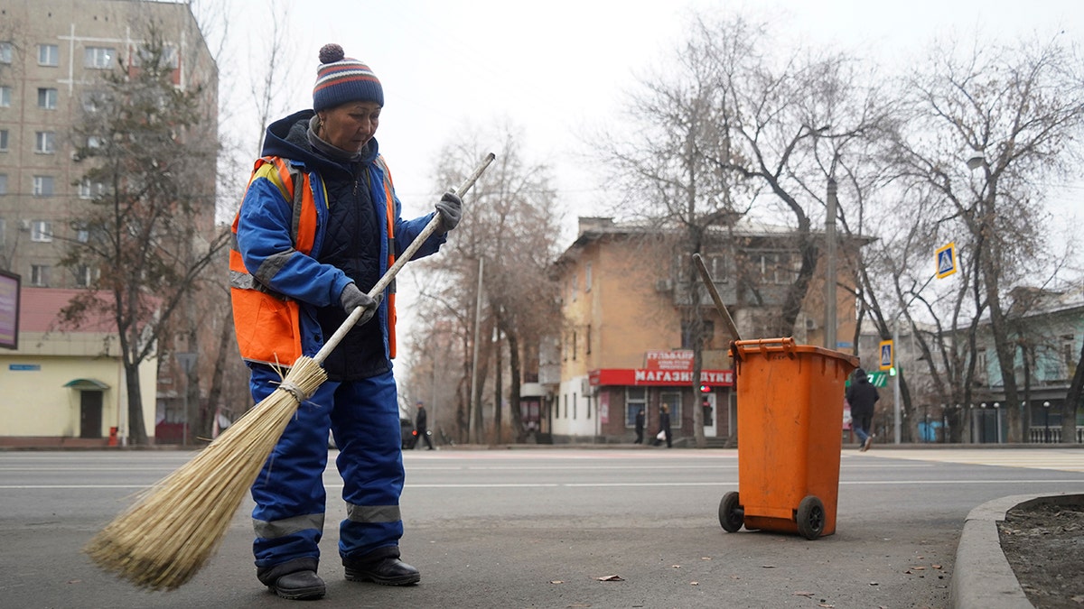 A municipal worker sweeps the street in Almaty, Kazakhstan, Monday, Jan. 10, 2022. 