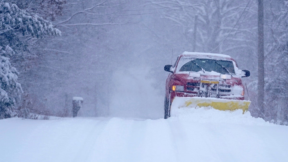 A small truck removes snow from an unplowed road, Friday, Jan. 7, 2022, in East Derry, New Hampshire.