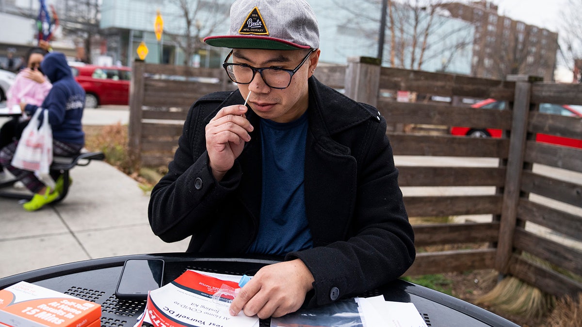 Aaron Salvador swabs his nose with a COVID-19 rapid antigen test kit outside the Watha T. Daniel-Shaw Neighborhood Library in Washington, D.C., on Wednesday, Dec. 29, 2021.