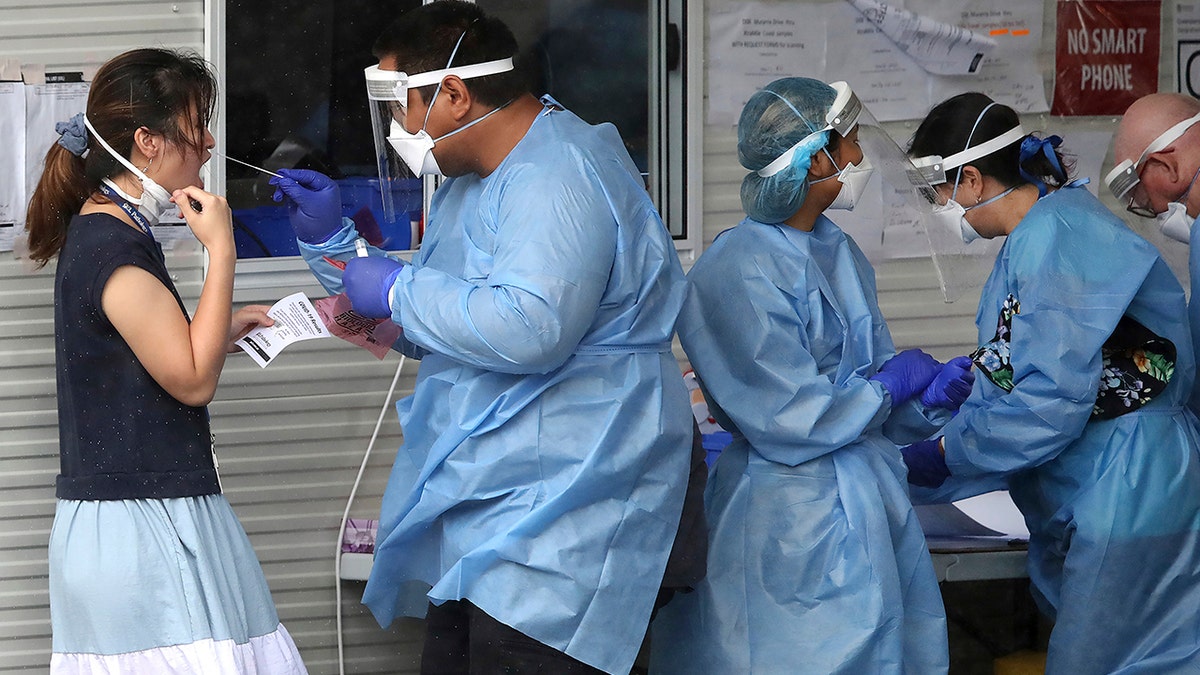 Health workers attend at a COVID-19 testing site in Brisbane, Australia, Friday, Jan. 7, 2022.