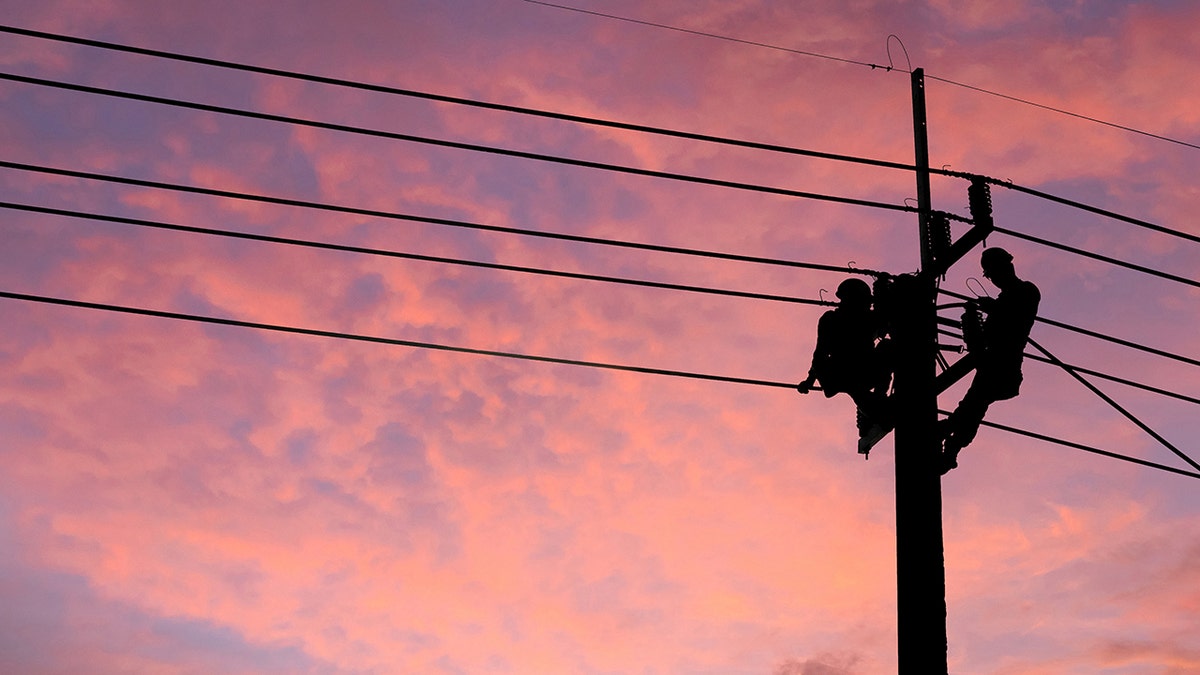 Electrician worker climbing electric power pole to repair the damaged power cable line problems after the storm. 