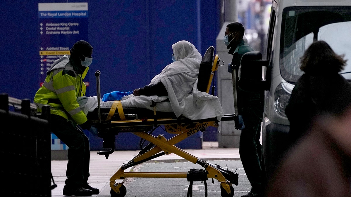 A patient is pushed on a trolley outside the Royal London Hospital in the Whitechapel area of east London, Thursday, Jan. 6, 2022. 