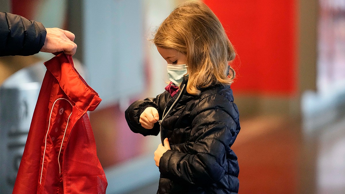 Six-year old Lotte puts on her jacket after she received her second coronavirus vaccination against the COVID-19 disease at the Laxness-Arena in Cologne, Germany, Friday, Jan. 7, 2022 where all participating children were rewarded for their vaccination. 