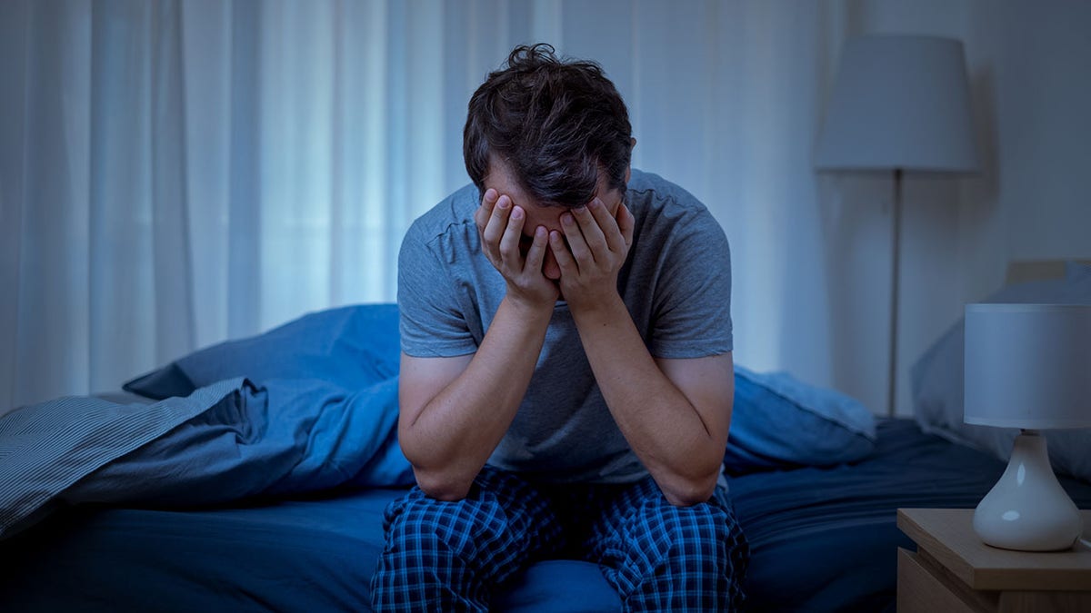 Man depressed in bed in his pajamas