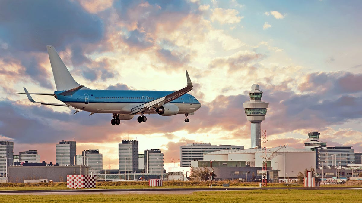 Airplane landing on Schiphol airport in Amsterdam in the Netherlands at sunset
