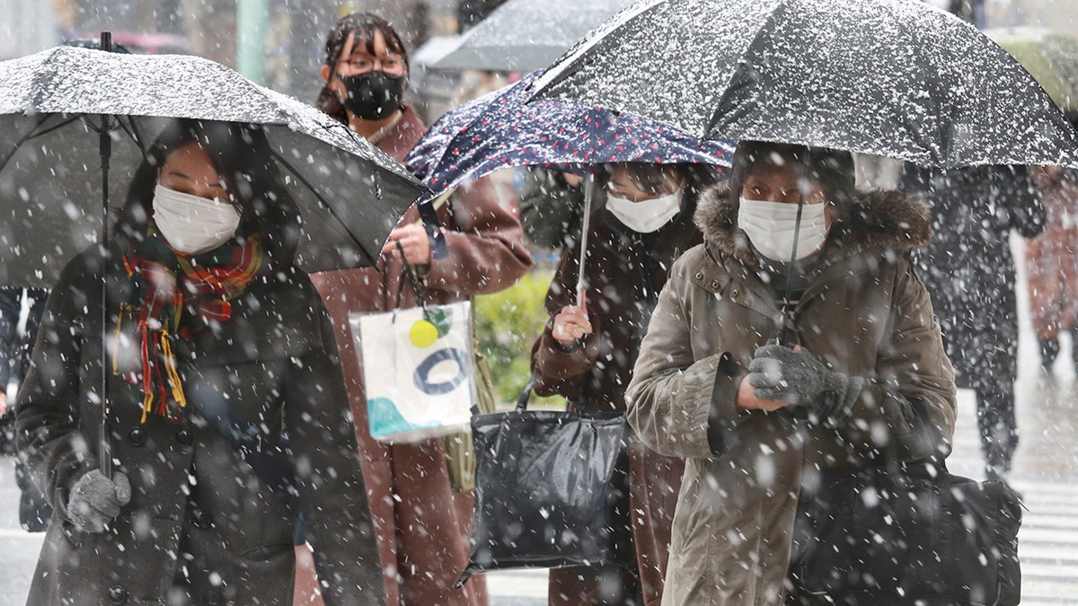 People wearing face masks to protect against the spread of the coronavirus walk on the street in Tokyo, Thursday, Jan. 6, 2022.