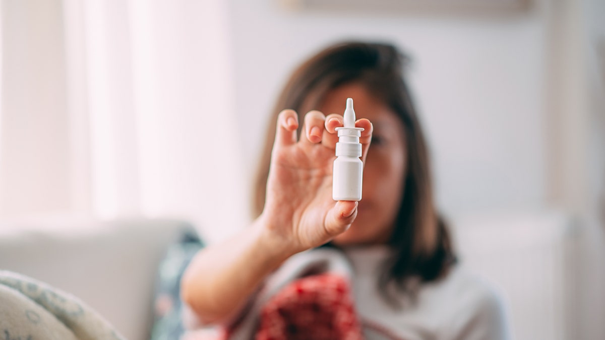 A woman holds nasal spray