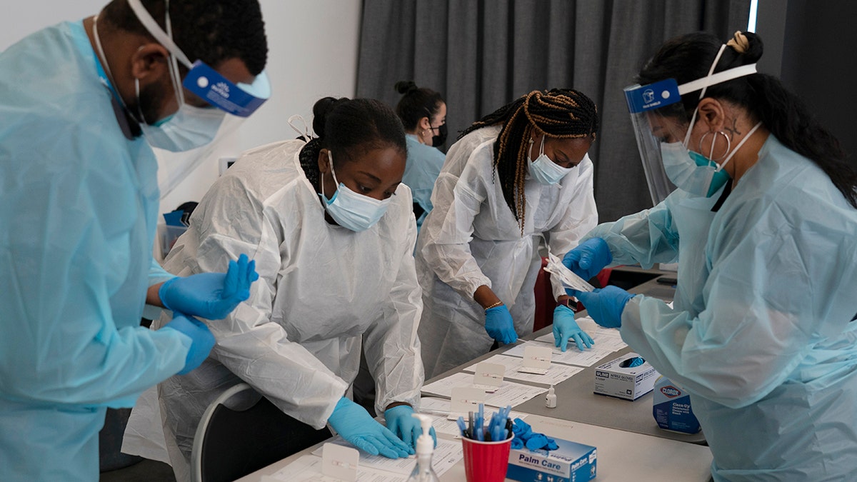 Health care workers Henry Paul, from left, Ray Akindele, Wilta Brutus and Leslie Powers process COVID-19 rapid antigen tests at a testing site in Long Beach, California, Jan. 6, 2022.