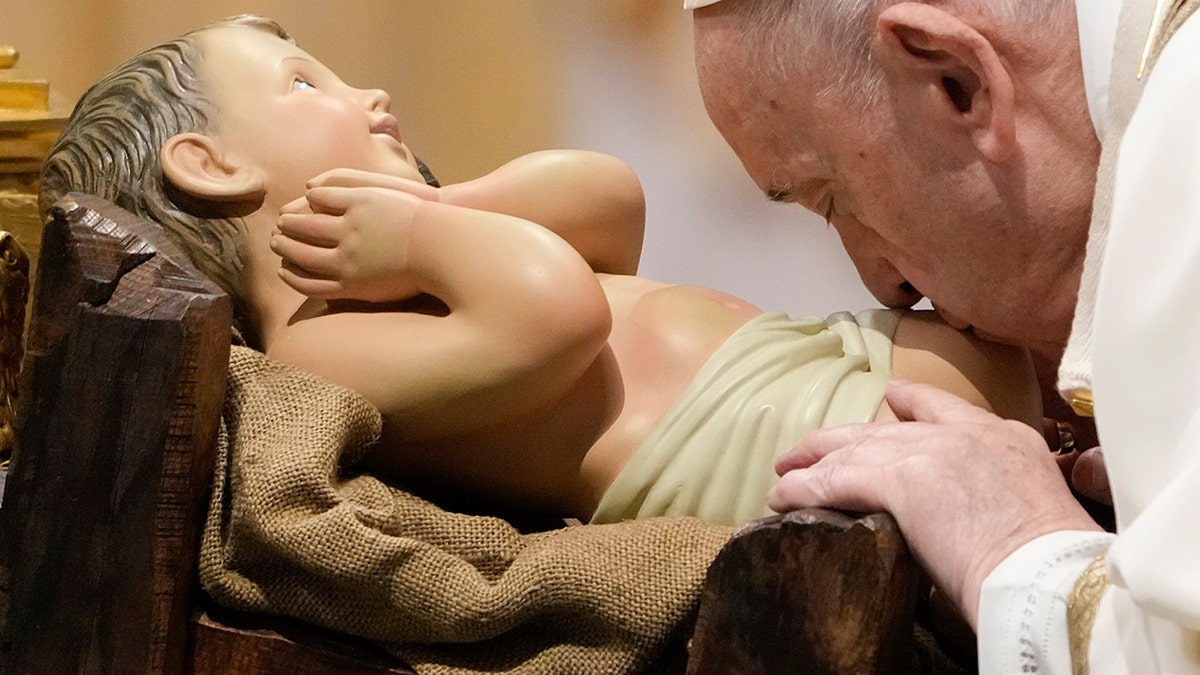 Pope Francis kisses a statue of baby Jesus as he celebrates an Epiphany mass in St. Peter's Basilica, at the Vatican, Thursday, Jan. 6, 2022. 