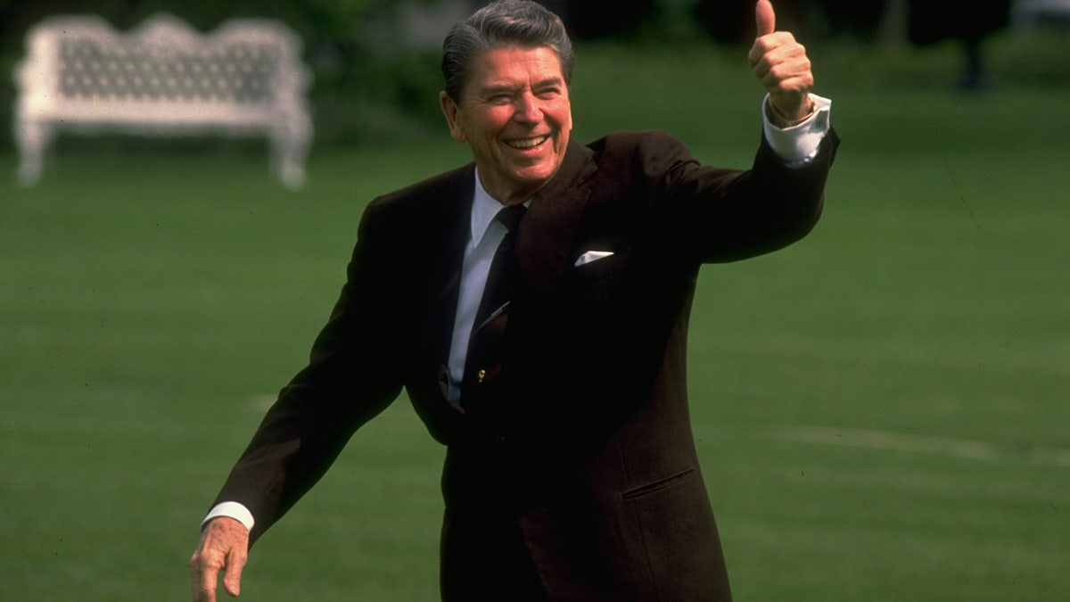 FILE – Pres. Ronald Reagan walking and giving thumbs up gesture on the South Lawn after returning from Massachusetts.