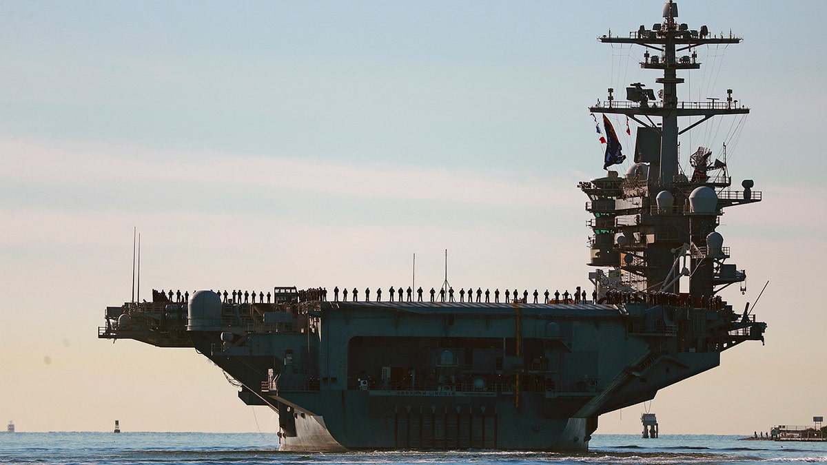 Sailors and marines line the deck of aircraft carrier USS Abraham Lincoln (CVN-72) as it deploys from San Diego on Monday, Jan. 3, 2021. 