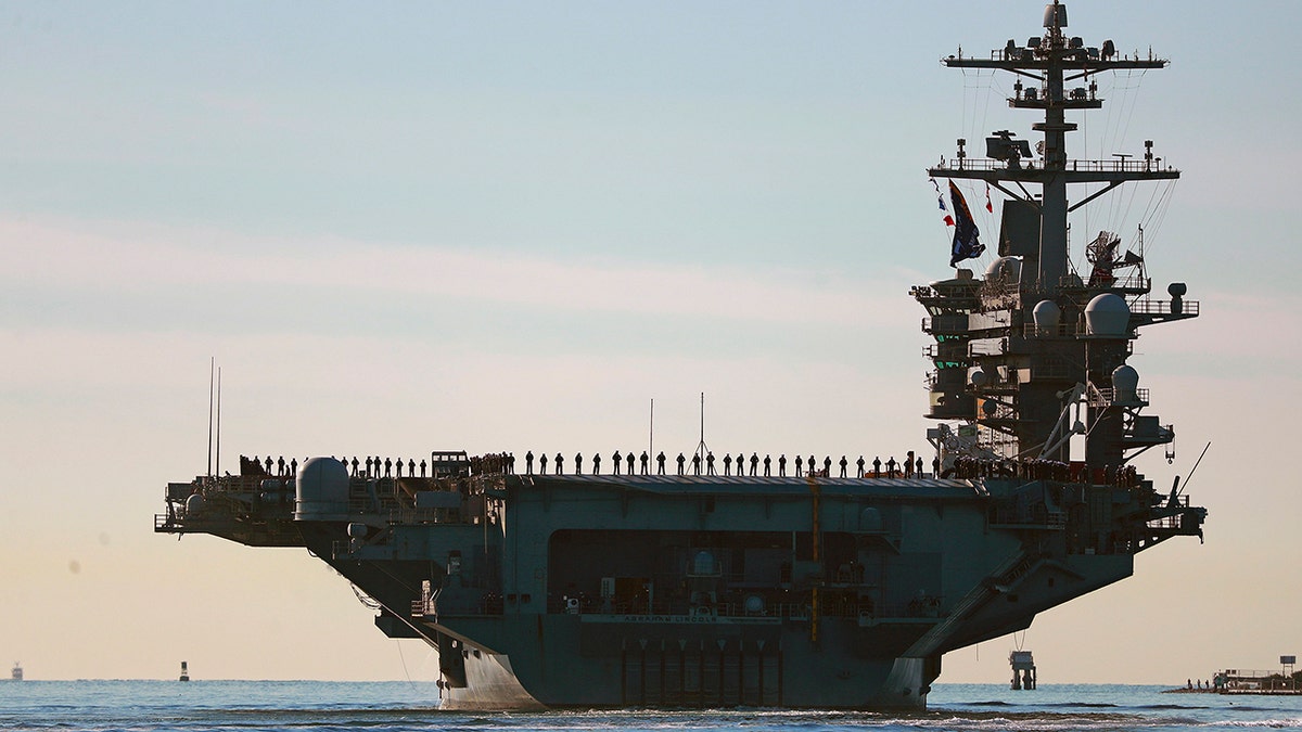Sailors and marines line the deck of aircraft carrier USS Abraham Lincoln (CVN-72) as it deploys from San Diego on Monday, Jan. 3, 2021.