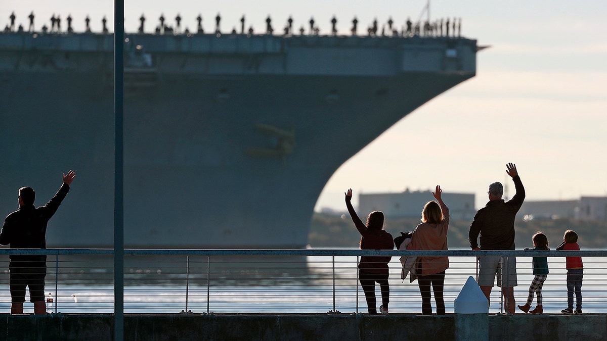 Families wave to the aircraft carrier USS Abraham Lincoln (CVN-72) as it deploys from San Diego, California, on Monday, Jan. 3, 2022.