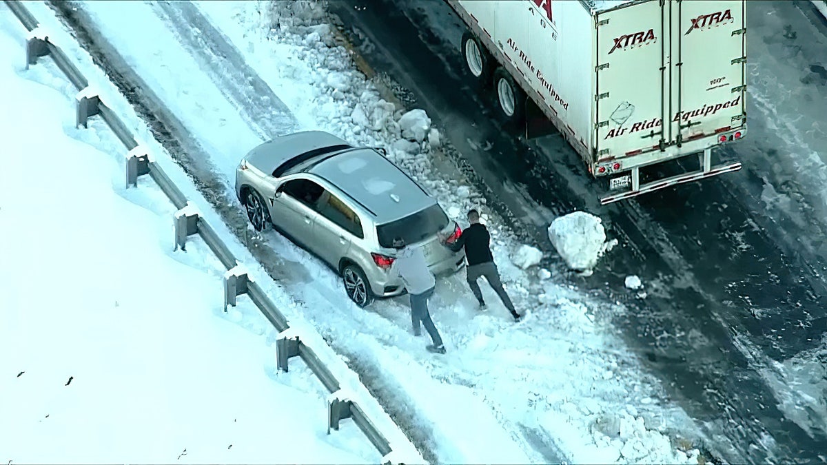 Stranded drivers are seen pushing a car along Interstate 95.