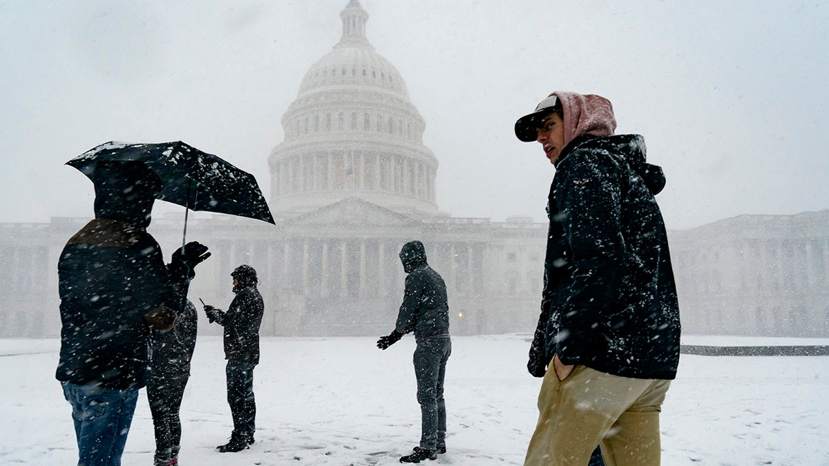 Visitors from France enjoy the scenery as a winter storm delivers heavy snow to the Capitol in Washington, Monday, Jan. 3, 2022.