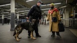 A commuter talks to a police officer with a dog at the Times Square subway station where Michelle Go was killed after being pushed onto subway tracks on January 15, in New York on January 18, 2022. (Photo by Ed JONES / AFP) (Photo by ED JONES/AFP via Getty Images)