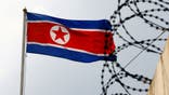 North Korea flag next to barb wire