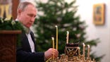 Russian President Vladimir Putin lights a candle during the Orthodox Christmas Liturgy in the Church of the Image of the Saviour Made Without Hands in Novo-Ogaryovo, outside Moscow, Russia, late Thursday, Jan. 6, 2022. Orthodox Christians celebrate Christmas on Jan. 7, in accordance with the Julian calendar. (Alexei Nikolsky/Sputnik, Kremlin Pool Photo via AP)