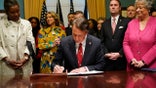 Virginia Gov. Glenn Youngkin, center, signs executive orders in the Governors conference room as Lt. Gov. Winsome Earle-Sears, left, Suzanne Youngkin, Second from left, Attorney General Jason Miyares, second from right, and Secretary of the Commonwealth, Kay Cole James, right, look on at the Capitol Saturday Jan. 15, 2022, in Richmond, Va. (AP Photo/Steve Helber)