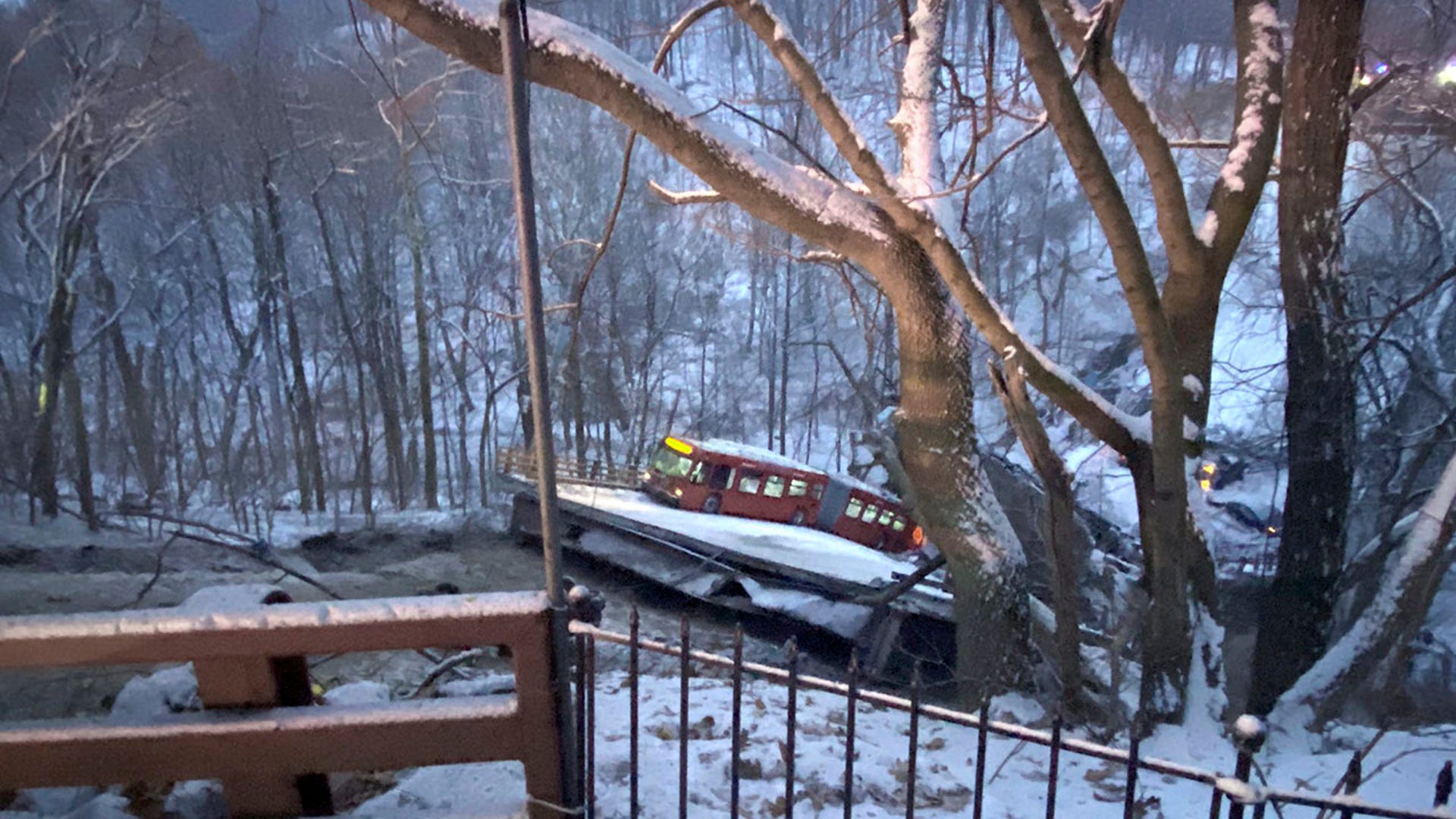 A commuter bus sits upright on a section of a collapsed bridge in Pittsburgh, on Friday, Jan. 28, 2022.  Police reported the span, on Forbes Avenue over Fern Hollow Creek in Frick Park, came down around 6 a.m. There were no initial reports of injuries, Pittsburgh Public Safety said on Twitter.  (Greg Barnhisel via AP)