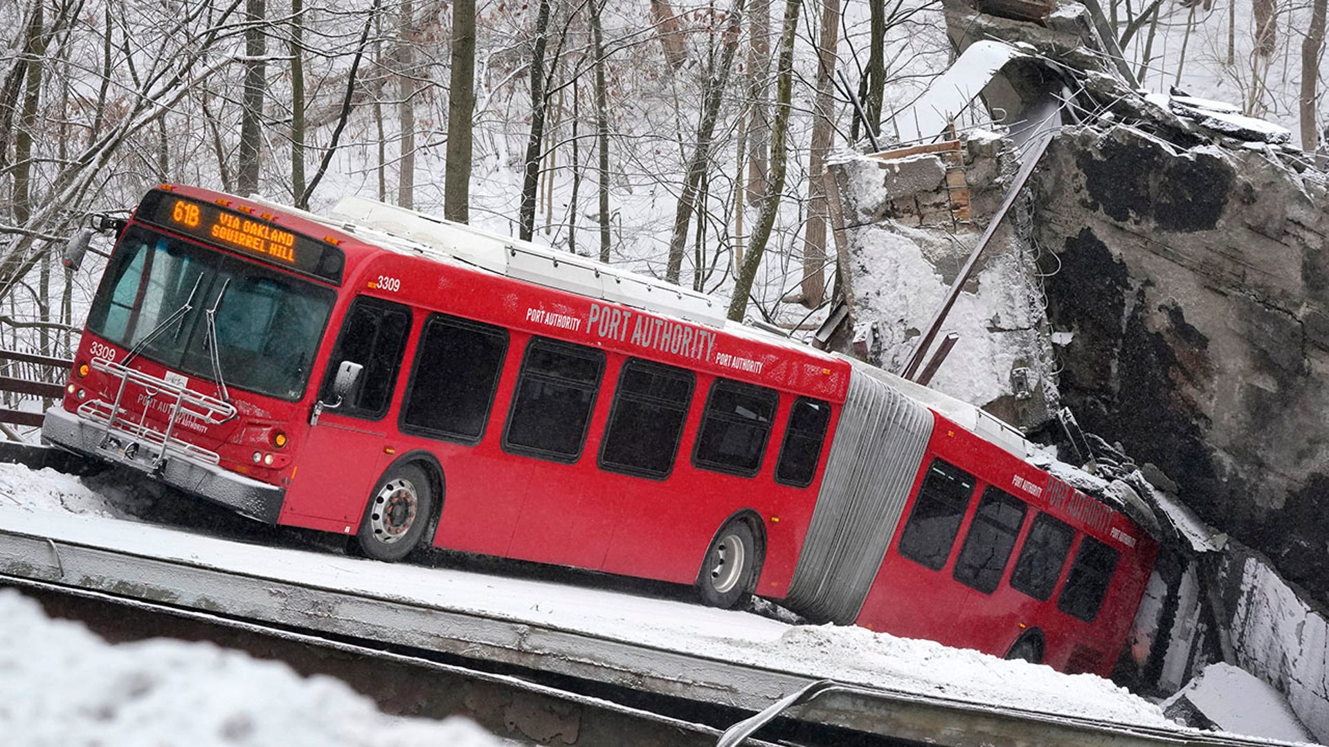 A Port Authority bus that was on a bridge when it collapsed Friday Jan. 28, 2022, is visible in Pittsburgh's East End. A two-lane bridge collapsed in Pittsburgh early Friday, prompting rescuers to rappel nearly 150 feet while others formed a human chain to help rescue multiple people from a dangling bus.(AP Photo/Gene J. Puskar)