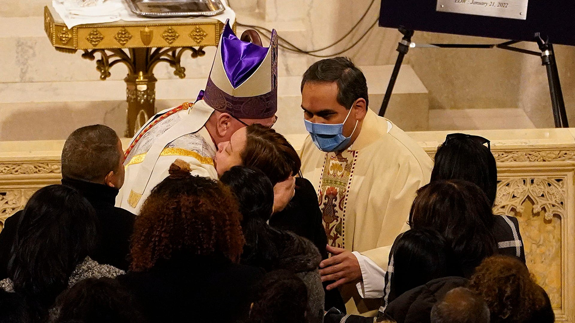 Cardinal Timothy Dolan, left, hugs family and friends of Officer Jason Rivera at the start of Rivera's funeral service inside St. Patrick's Cathedral, Friday, Jan. 28, 2022, in New York. Rivera and his partner, officer Wilbert Mora, were fatally wounded when a gunman ambushed them in an apartment as they responded to a family dispute last week. (AP Photo/Mary Altaffer, POOL)