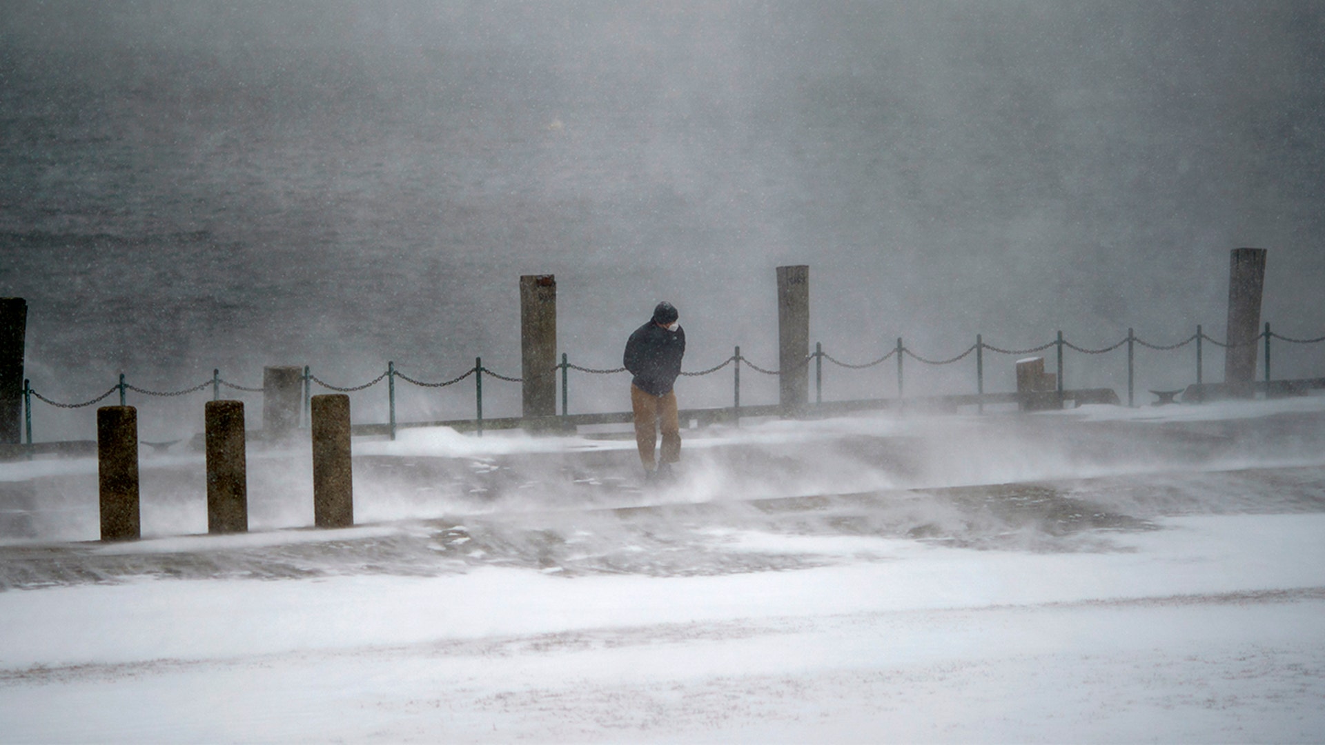 A pedestrian walks through a gust of wind along the waterfront in India Point Park in Providence, R.I., Saturday, Jan. 29, 2022.