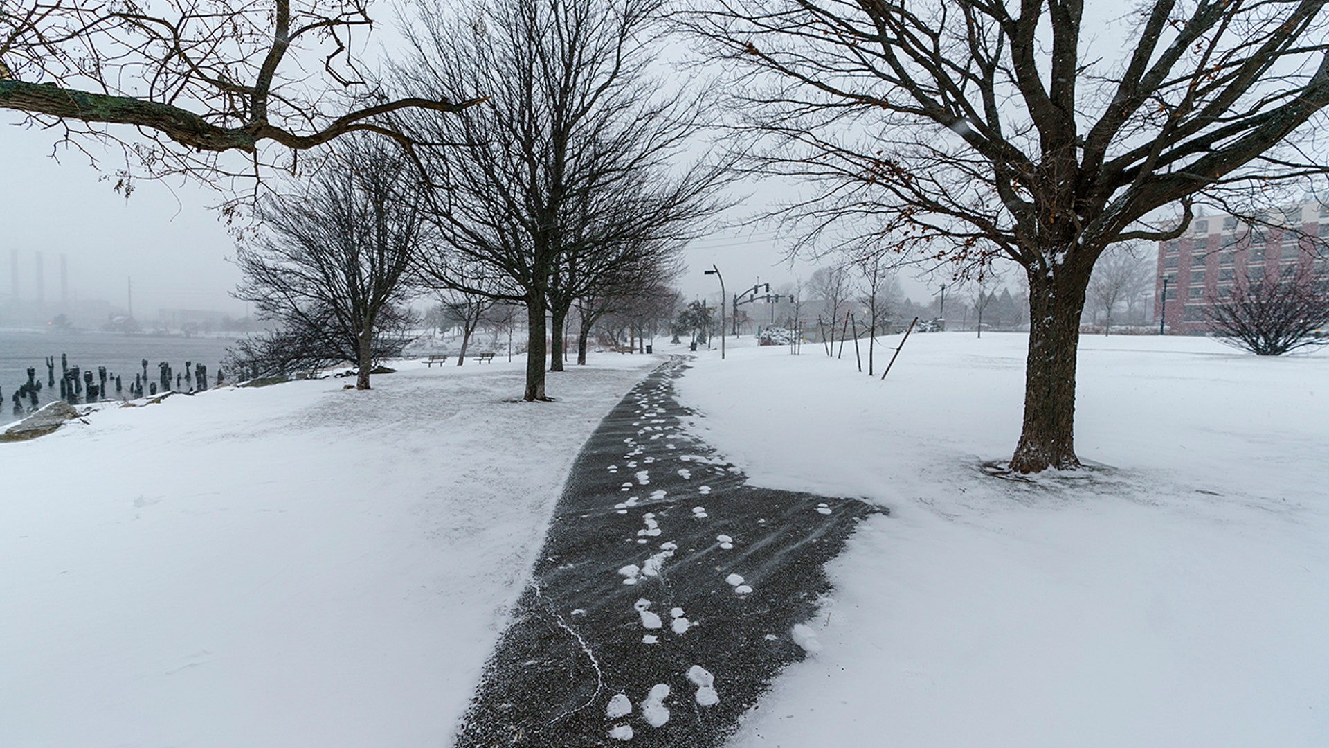 A pedestrian walks through a gust of wind along the waterfront in India Point Park in Providence, R.I., Saturday, Jan. 29, 2022.
