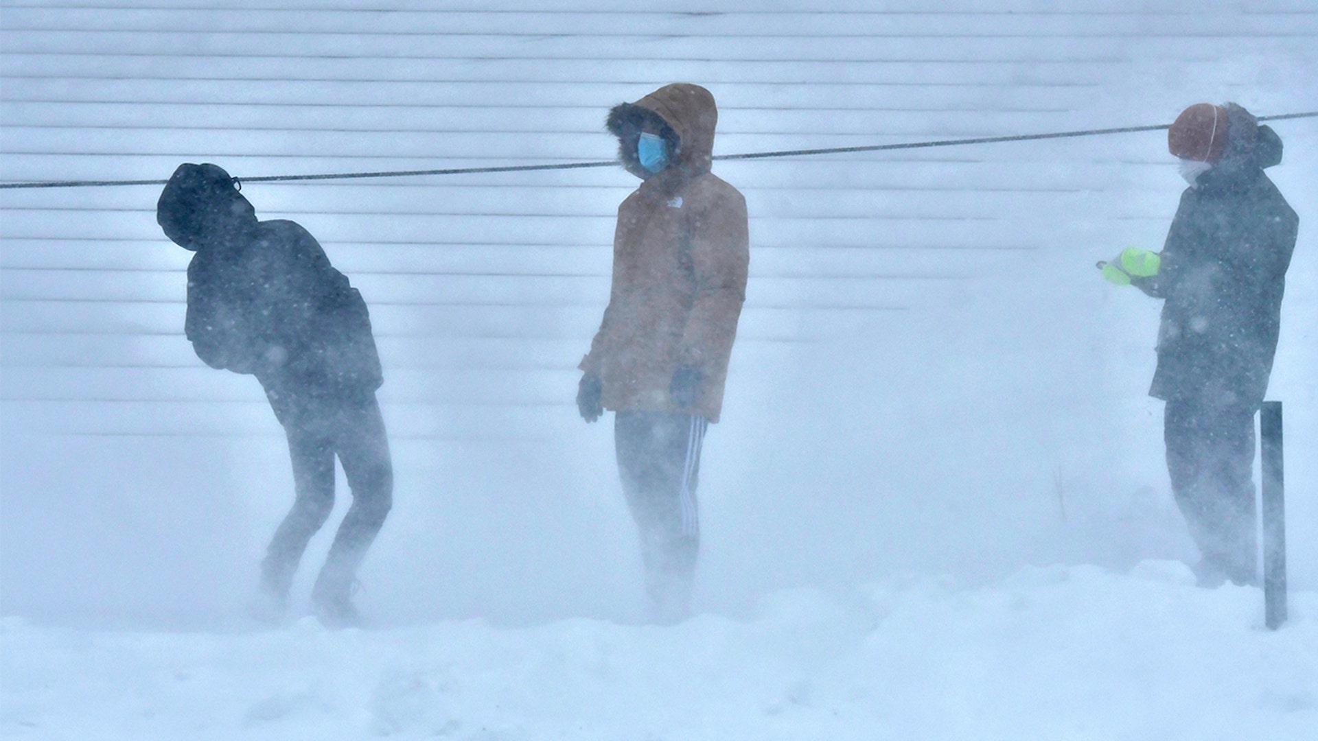 A group of Harvard students react to the wind while taking turns sledding down the steps of the Widener Library in Harvard Yard, during a storm that was projected to bring up to two feet of snow to the region, Saturday, Jan. 29, 2022, in Cambridge, Mass.