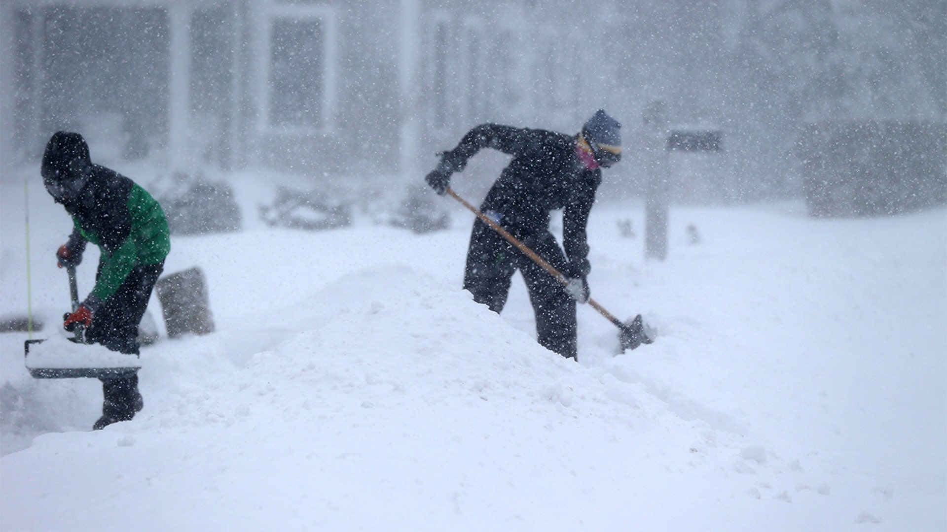 People shovel in the heavy snow and wind in Cohasset, MA on Jan. 29, 2022.