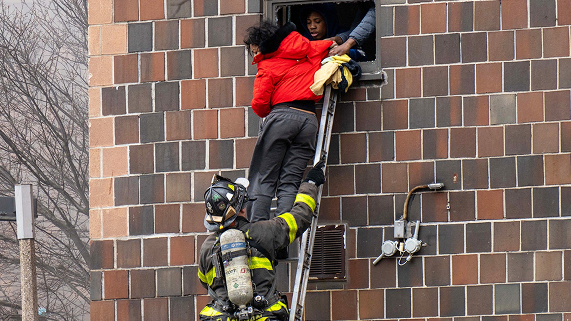A firefighter helps a resident escape the Bronx apartment building fire