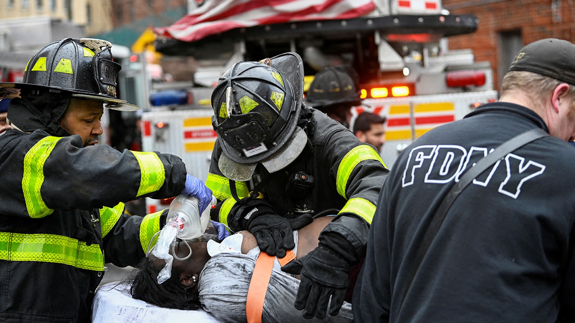 A victim of the Bronx apartment fire is helped by firefighters