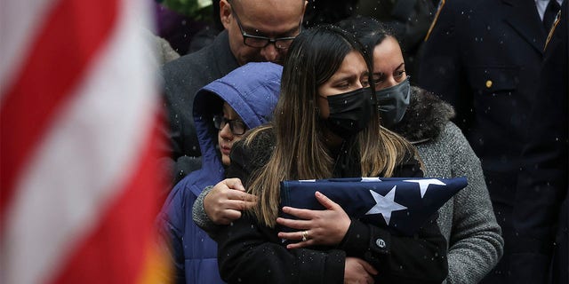 Dominique Rivera, left, wife of, NYPD Officer Jason Rivera watches as his casket is loaded into a hearse outside St. Patrick's Cathedral after his funeral service, Friday, Jan. 28, 2022, in New York. Rivera and his partner, Officer Wilbert Mora, were fatally wounded when a gunman ambushed them in an apartment as they responded to a family dispute last week. (AP Photo/Yuki Iwamura)