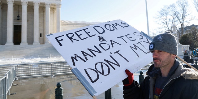 A lone protester stands outside the U.S. Supreme Court as it hears arguments against the Biden administration's nationwide vaccine-or-test-and-mask COVID-19 mandates, in Washington, Jan. 7, 2022.
