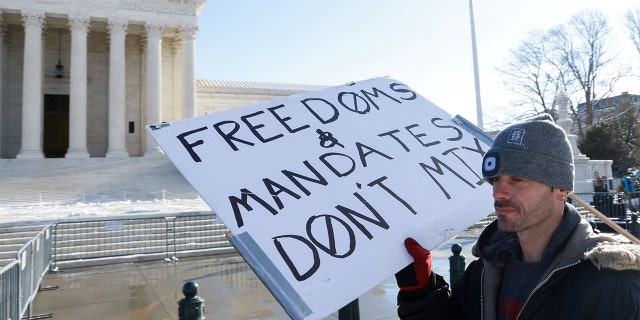 A lone protester stands outside the U.S. Supreme Court as it hears arguments against the Biden administration's nationwide vaccine-or-test-and-mask COVID-19 mandates, in Washington, Jan. 7, 2022.