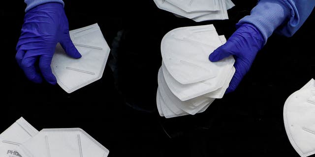 FILE PHOTO: A workers inspects an N95 respirator during manufacturing at Protective Health Gear (PHG) in Paterson, New Jersey, U.S., January 14, 2022.