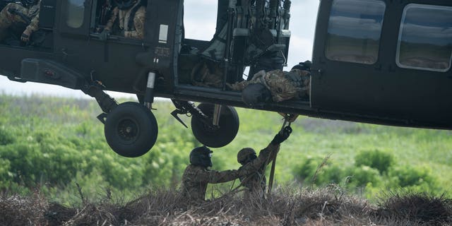 Engineers hook a bundle of Christmas trees to a helicopter, a similar technique they'd use to haul emergency supplies.