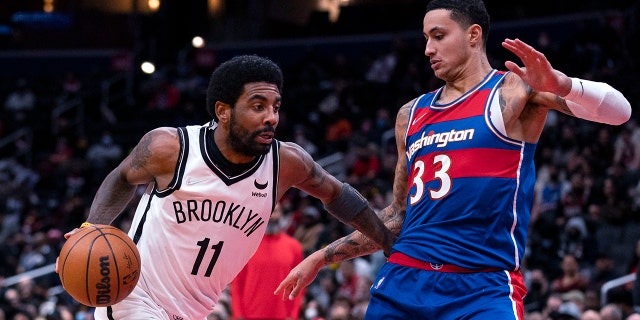 Brooklyn Nets guard Kyrie Irving (11) drives to the basket against Washington Wizards forward Kyle Kuzma (33) during the first half of an NBA basketball game Wednesday, Jan.. 19, 2022, in Washington.