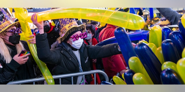 Revelers are given balloons as they gather in Times Square in New York Friday, Dec. 31, 2021 while attending New Year's Eve celebrations.