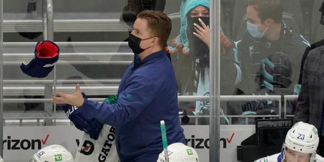 Seattle Kraken fan Nadia Popovici, center, reacts after she was introduced along with Vancouver Canucks assistant equipment manager Brian "Red" Hamilton, standing, during the first period of an NHL hockey game Saturday, Jan. 1, 2022, in Seattle.