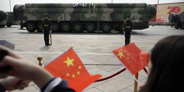 Spectators wave Chinese flags as military vehicles carrying DF-41 nuclear ballistic missiles roll during a parade to commemorate the 70th anniversary of the founding of Communist China in Beijing on Oct. 1, 2019.