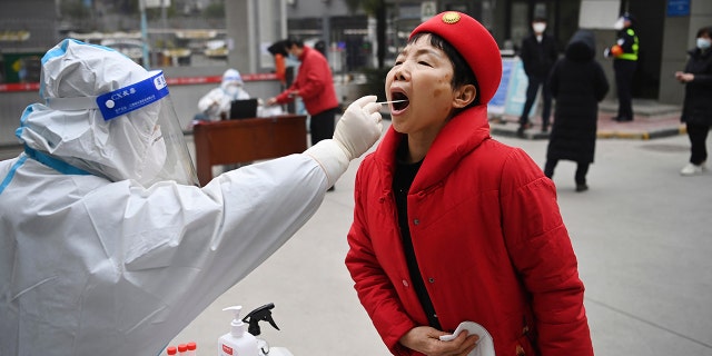 Nesta foto divulgada pela Agência de Notícias Xinhua da China, um trabalhador vestindo roupas de proteção realiza um teste COVID-19 em uma mulher em um local de testes em Xi'an, província de Shaanxi, noroeste da China, na terça-feira, 4 de janeiro de 2022. (Tao Ming / Xinhua via AP)