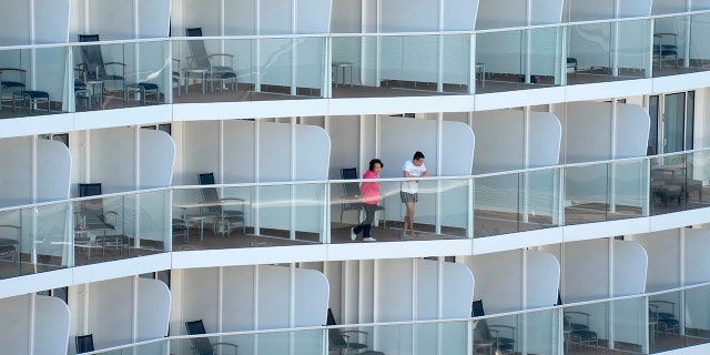 Passengers look out from the Spectrum of the Seas cruise ship docked at Kai Tak cruise terminal in Hong Kong Wednesday, Jan. 5, 2022. (AP Photo/Vincent Yu)