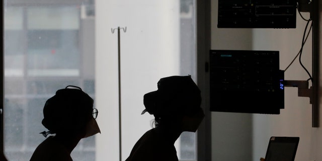 Nurses look at a screen near rooms with patients suffering from COVID-19, in the ICU unit at the Charles Nicolle public hospital, in Rouen, France, April 15, 2021. (AP Photo/Christophe Ena, File)