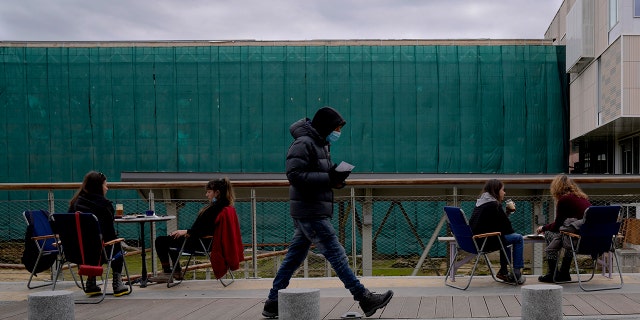 Ein Mann, der eine Gesichtsmaske zum Schutz vor dem Coronavirus trägt, geht am Mittwoch, den 5. Januar 2022, an Kunden eines Cafés im Zentrum von Nikosia, Zypern, vorbei.