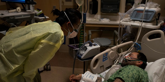 Registered nurse Emily Yu, left, talks to Paul Altamirano, a 50-year-old COVID-19 patient, at Providence Holy Cross Medical Center in Los Angeles, Dec. 13, 2021. (AP Photo/Jae C. Hong, File)